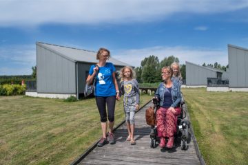 Eelke met vriendin en kinderen voor de rolstoeltoegankelijke bungalow op Provinciaal domein de Gavers