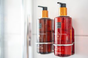 twee rode flesjes Rituals in een houder aan de muur