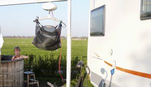 In zit naast een camper in een hottub met op de voorgrond een tilliftsysteem aan een staande beugel over de hottub heen