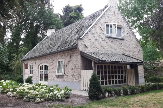 The Escape, bakstenen huisje met puntdak en grote ramen met hortensia's in de tuin