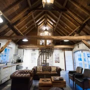 overzichtsfoto van de woonkamer met keuken en hoog puntdak met bruine houten balken