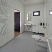 Rolstoeltoegankelijke badkamer, toilet met beugels, onberijdbare wastafel en schuifdeur