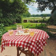 Uitzicht vanuit B&B, met tafeltje met roodwit geblokt kleedje op de voorgrond en daarachter een weids groen uitzicht