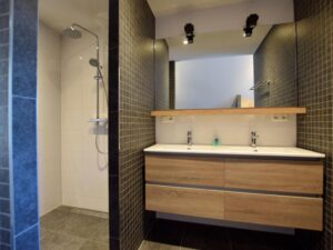douche hoek , gescheiden door een muur van een wastafelmeubel met twee wasbakken