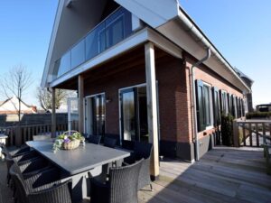 Huis met puntdak en terras met tuinmeubilair en twee openslaande deuren