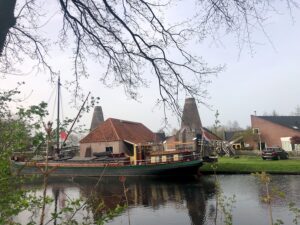 aan het water gelegen gebouw met twee brede hoge schoorstenen ernaast.