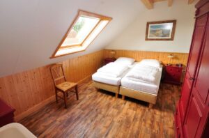2 boxspringbedden, houten vloer, schuin dak met dakraam. Gele lambrisering